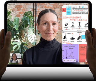 Vooraanzicht van iPad Pro, horizontale stand, kleur spacezwart, afgeronde hoeken, zwarte rand rond het display, handen houden de linker- en rechterkant vast, display toont een FaceTime-gesprek dat live wordt vertaald en een educatieve app met een presentatie van ‘Comparative Mythology’ met tekst, diagrammen en handgeschreven notities